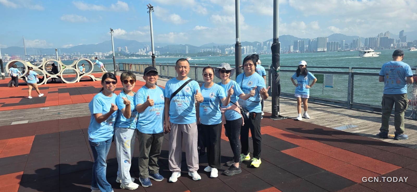 數名身穿淺藍色活動上衣的參加者在海旁合照。
