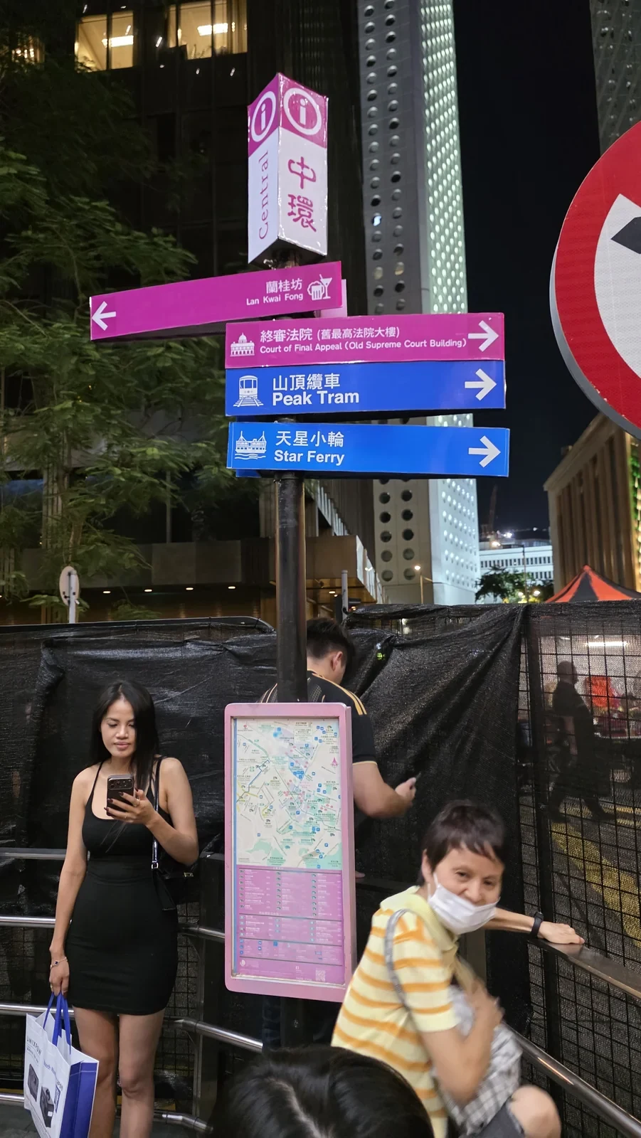 夜間多語城市導向牌、地圖與行人（2026年10月18日；說明性配圖）。