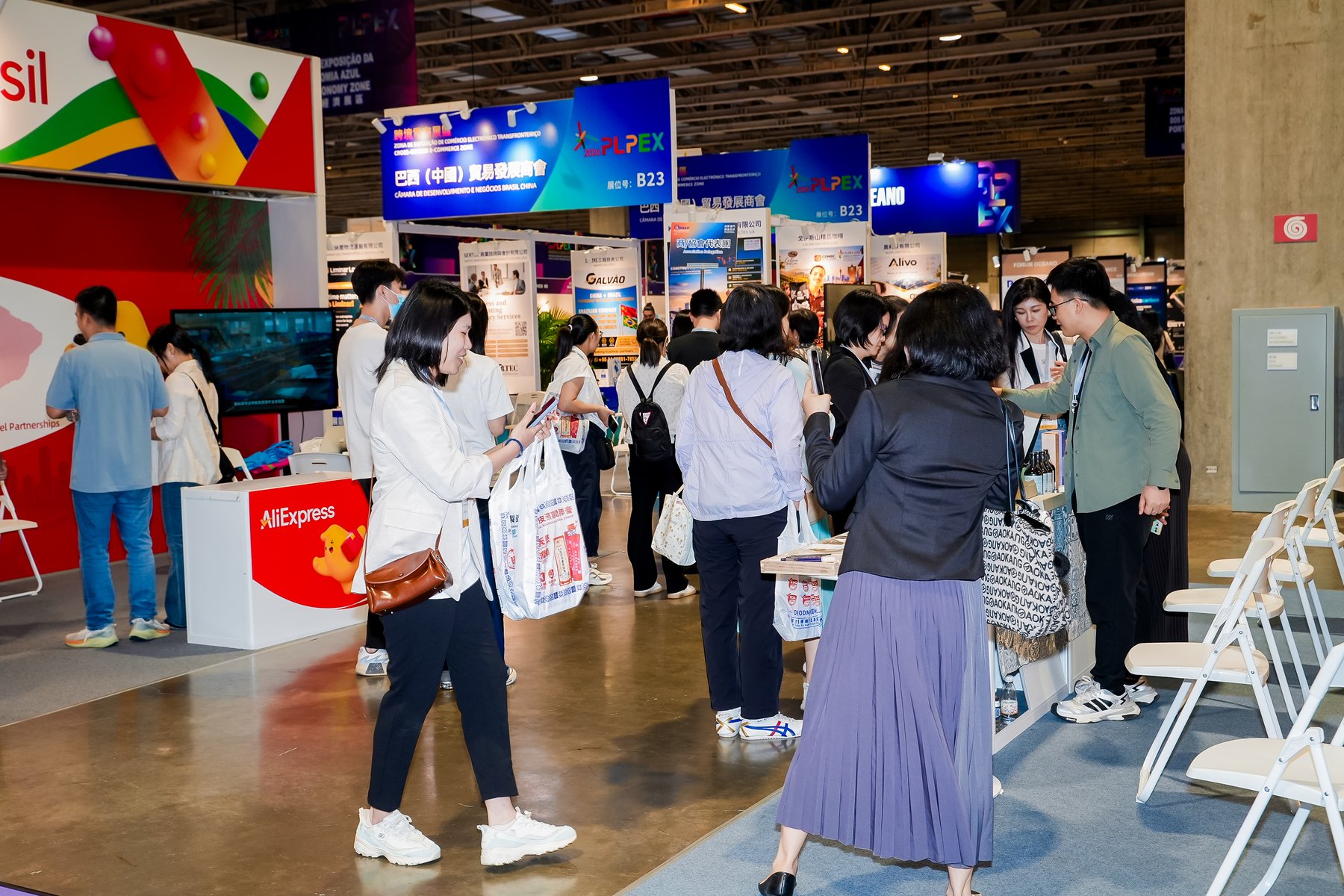參觀者在PLPEX展區內走動及觀看展位，背景多處可見PLPEX標示。